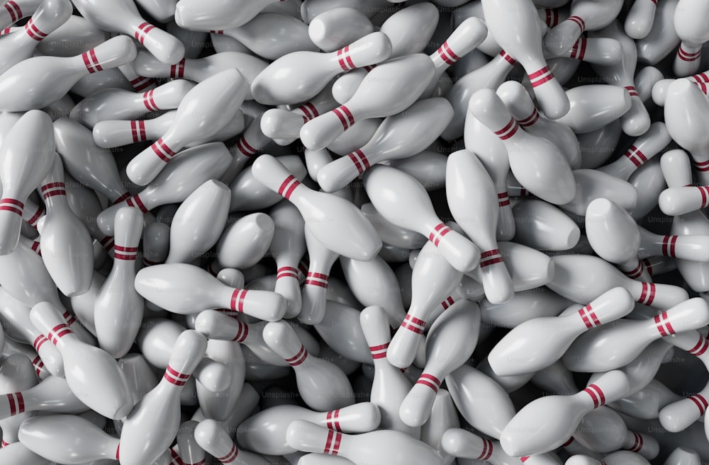 a pile of white bowling pins with red pins on them