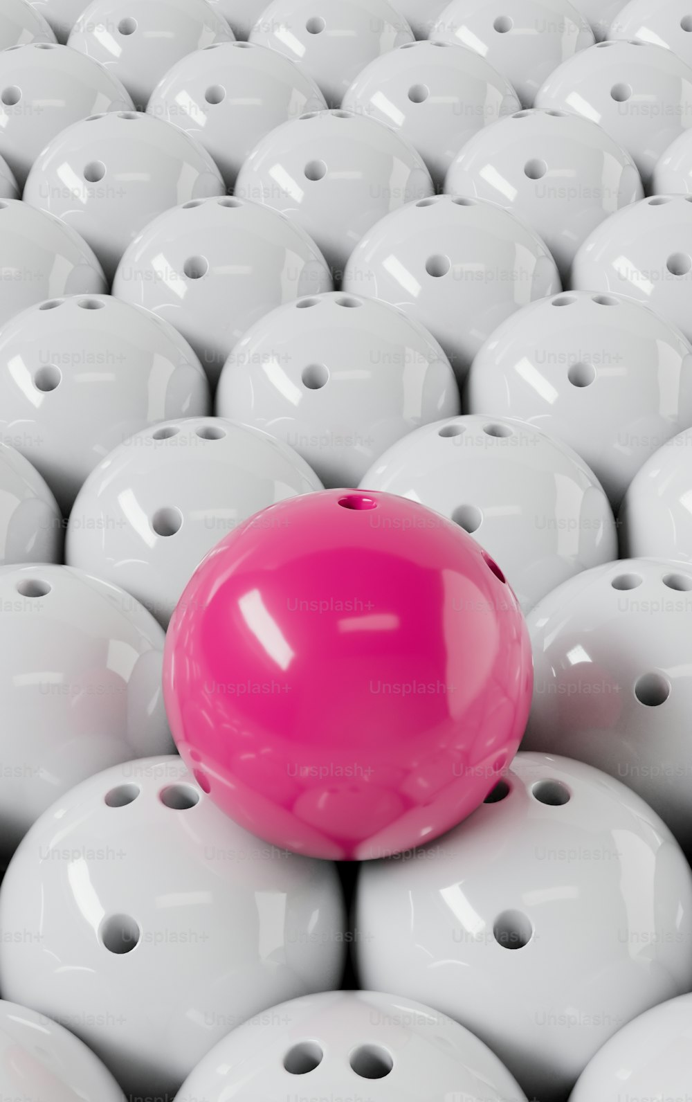 una palla rosa seduta sopra un grande gruppo di palline bianche