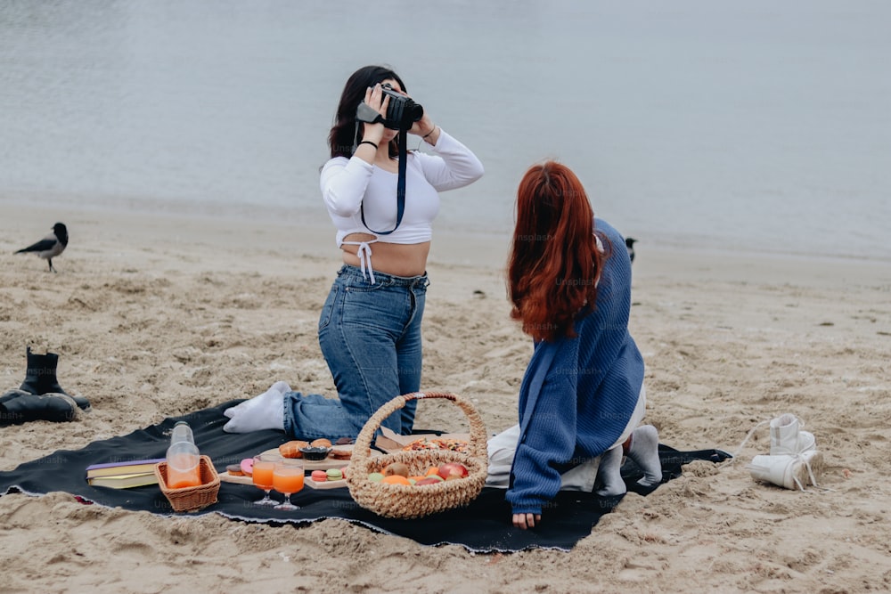 a woman taking a picture of another woman on the beach