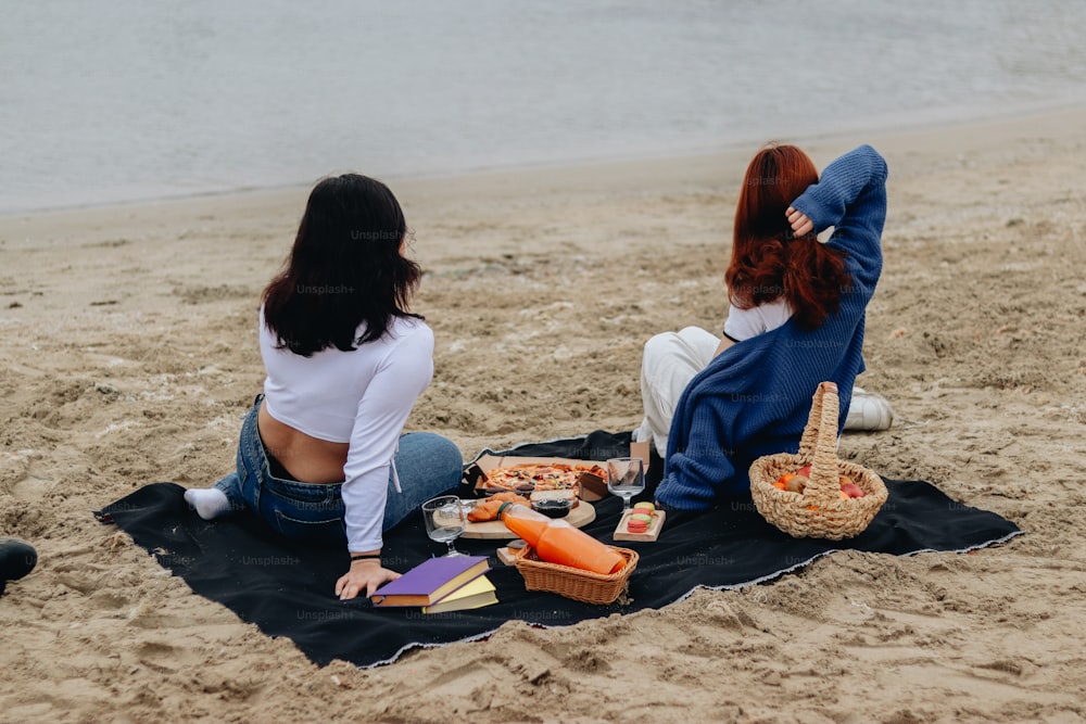 모래 사장 위에 앉아있는 두 명의 여성