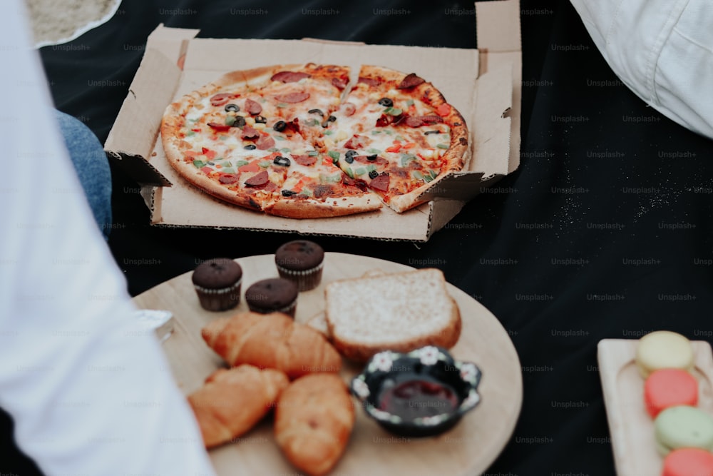 a pizza sitting on top of a table next to a box of doughnuts