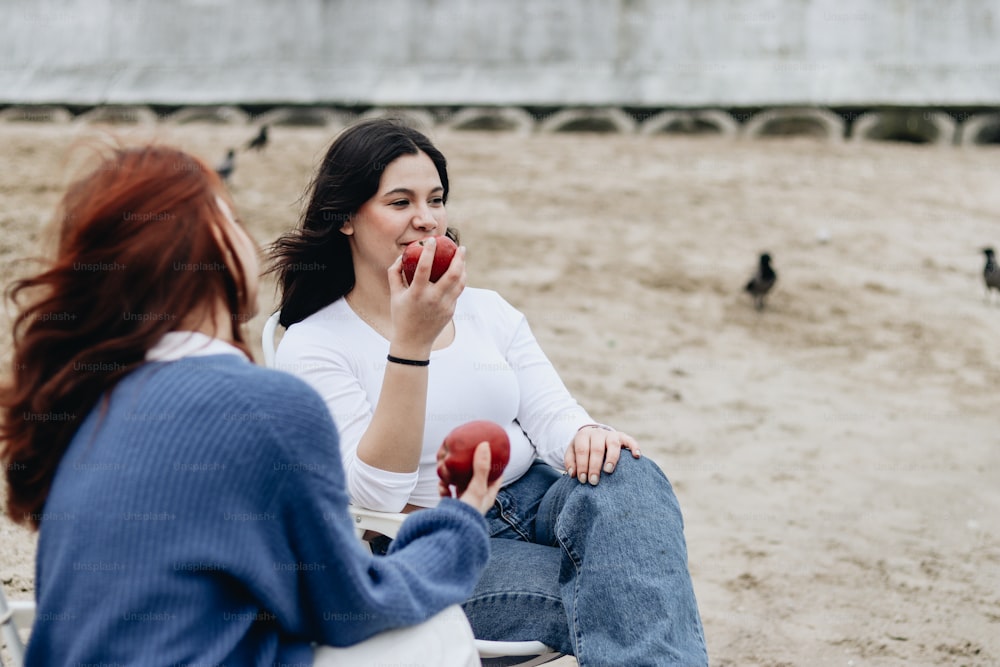 a couple of women sitting on top of a sandy beach