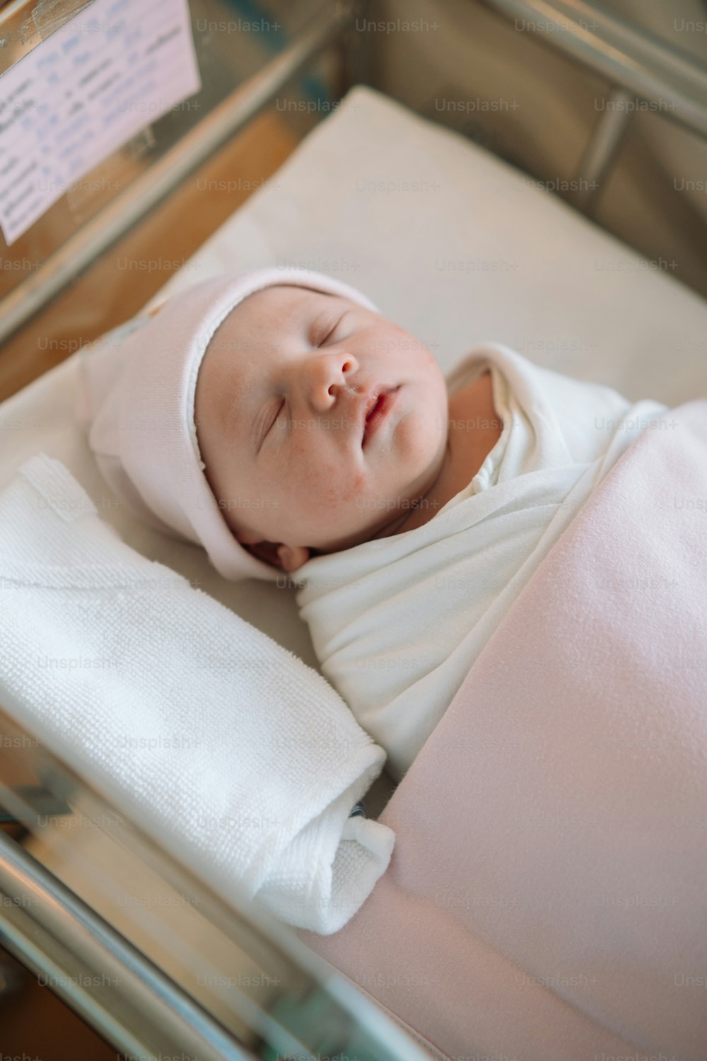 a baby is sleeping in a glass crib