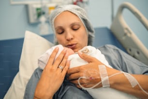 Una mujer sosteniendo a un bebé en una cama de hospital