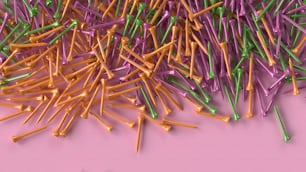 uma pilha de palitos de dente coloridos em uma superfície rosa