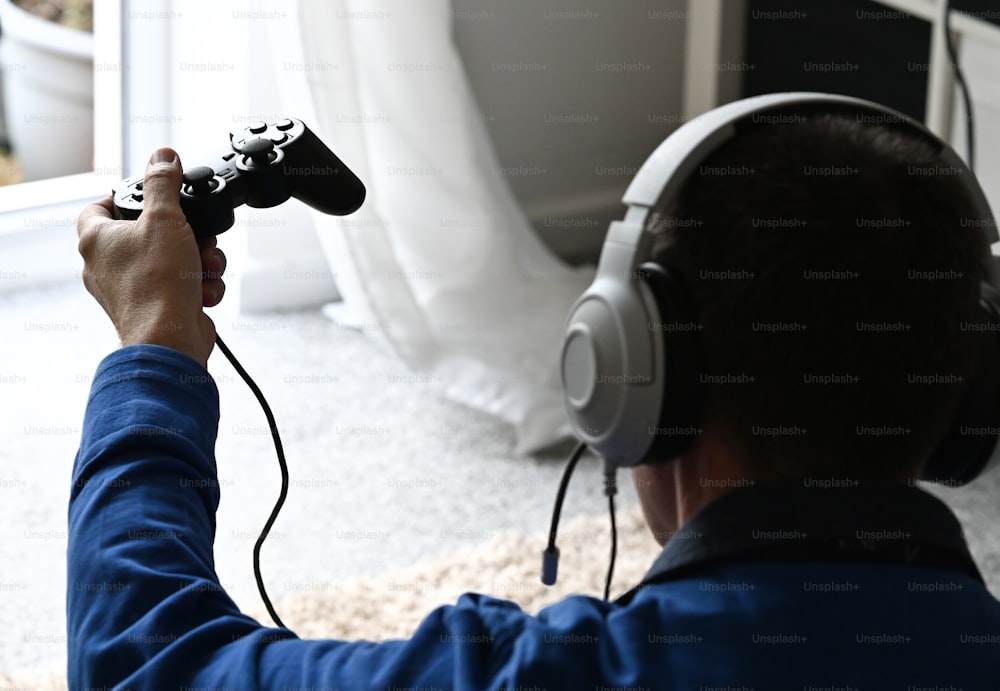 �男がヘッドフォンでビデオゲームをプレイしている