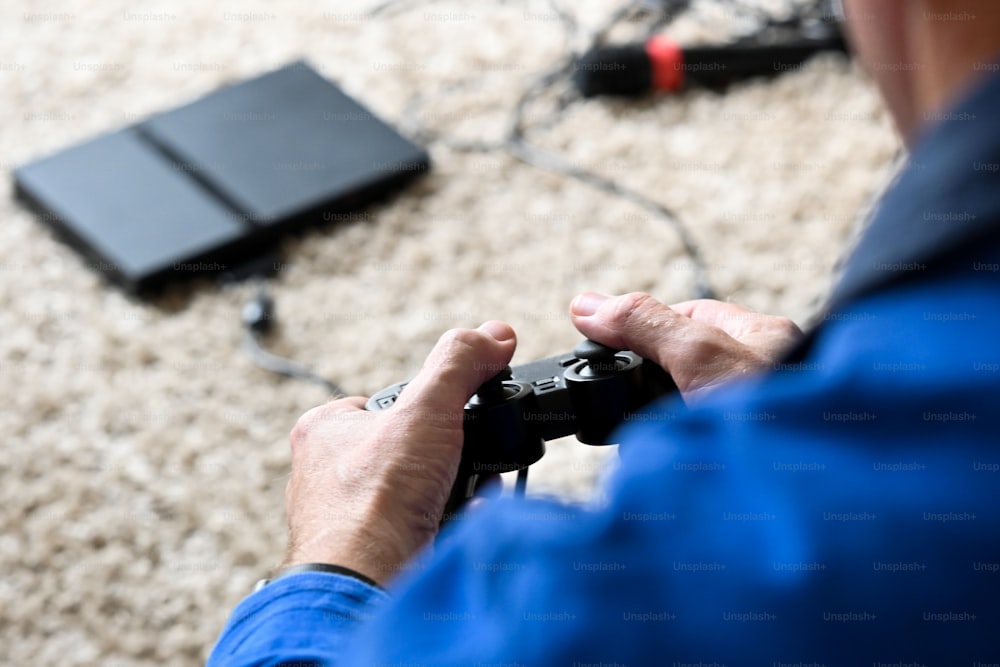 Un hombre está jugando un videojuego en el suelo