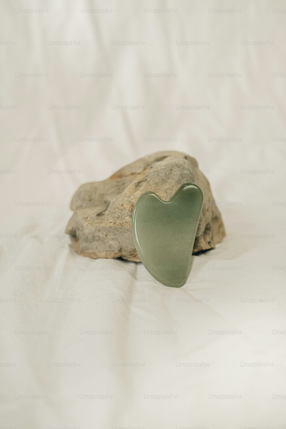 a green heart shaped object sitting on top of a rock