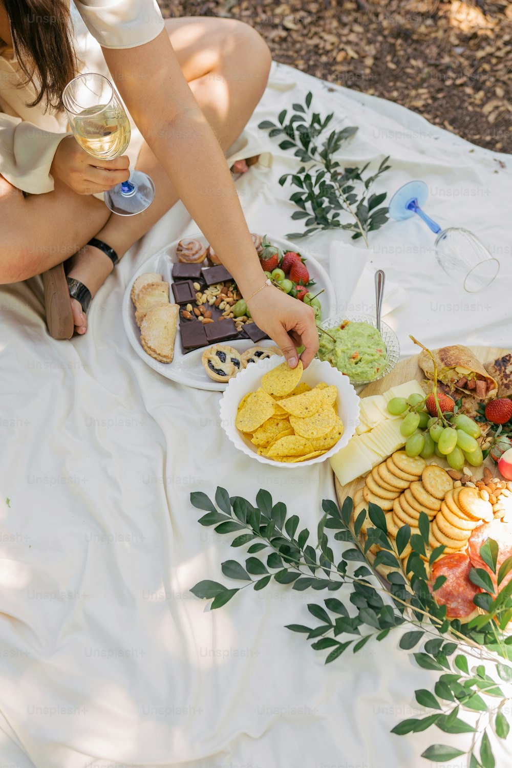 a woman sitting on a blanket with a plate of food
