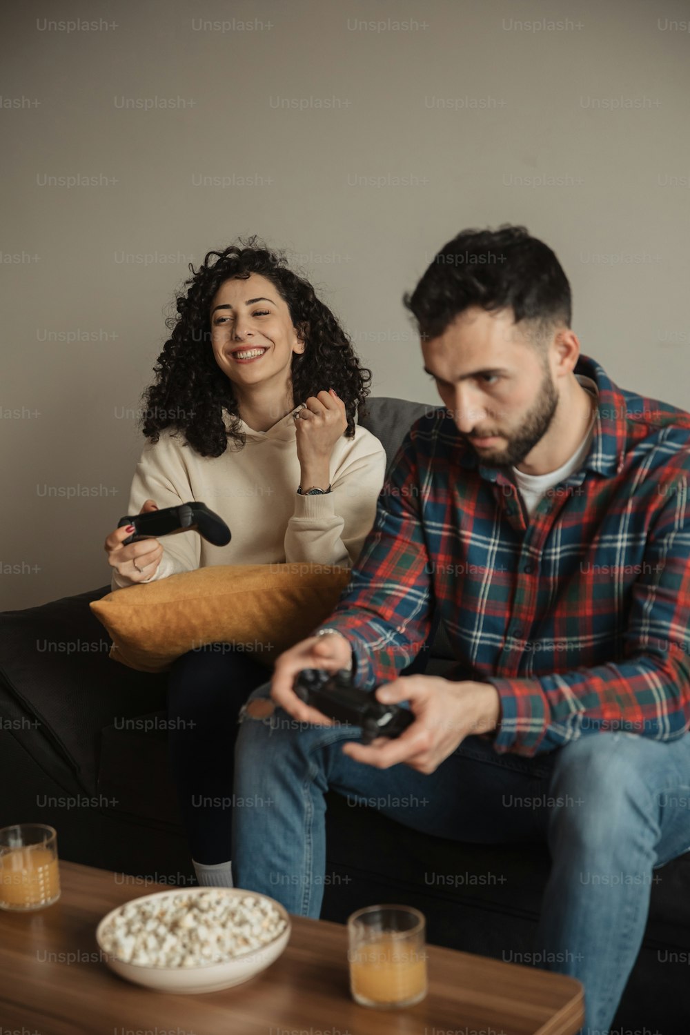 a man sitting on a couch next to a woman holding a remote control