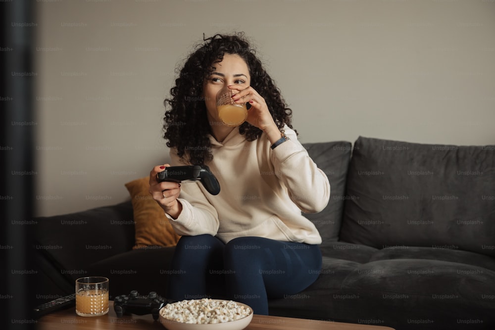 uma mulher sentada em um sofá comendo pipoca