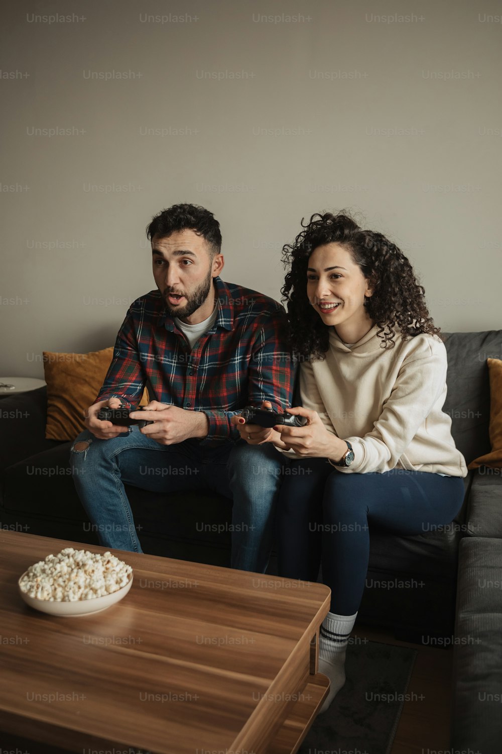 ソファに座ってビデオゲームをしている男女
