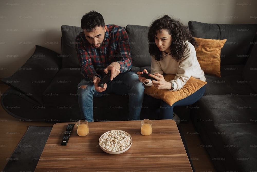 Ein Mann und eine Frau sitzen auf einer Couch und spielen Videospiele