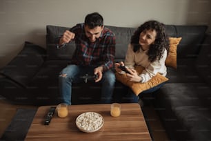a man and woman sitting on a couch playing video games