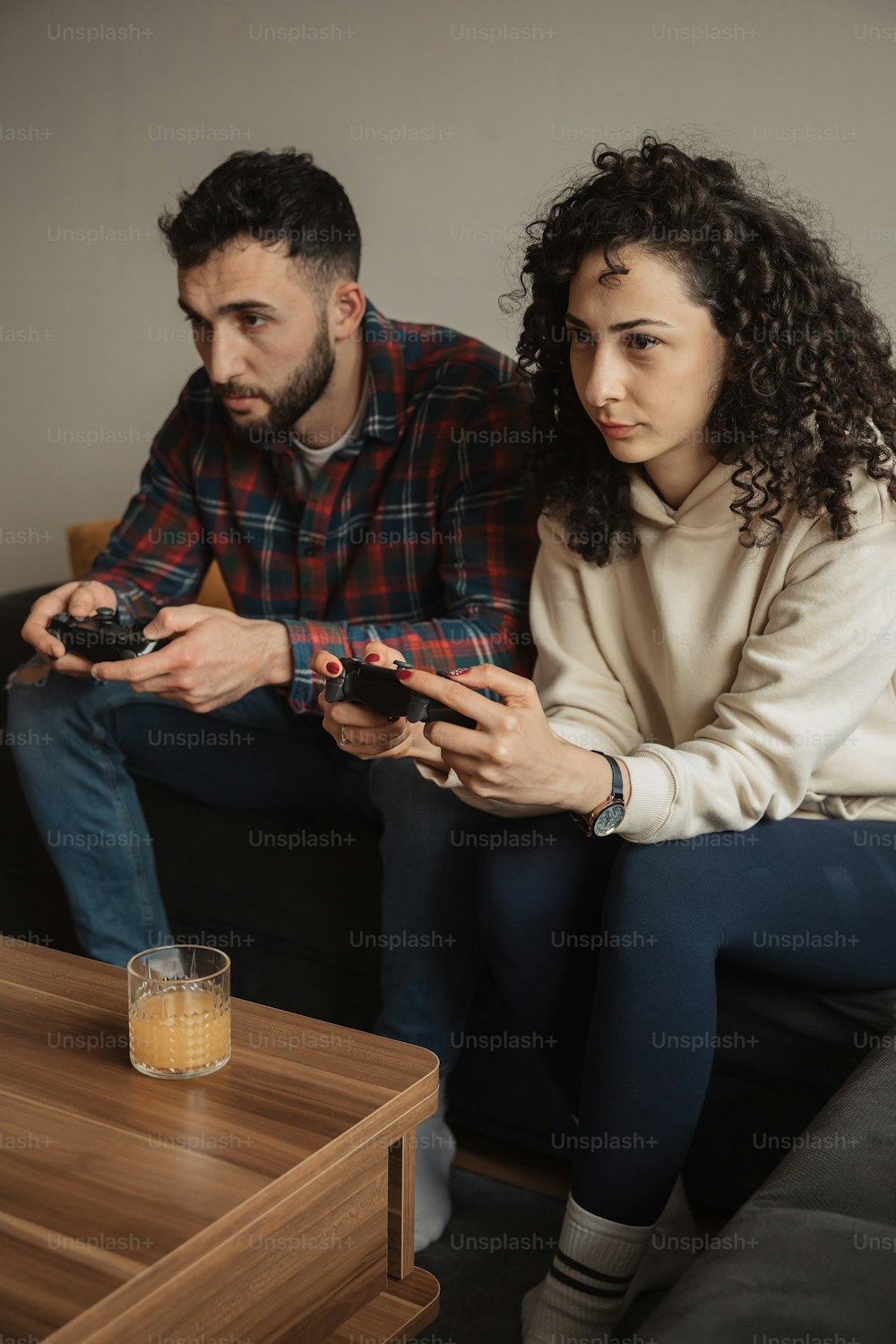 a man and a woman sitting on a couch holding remotes