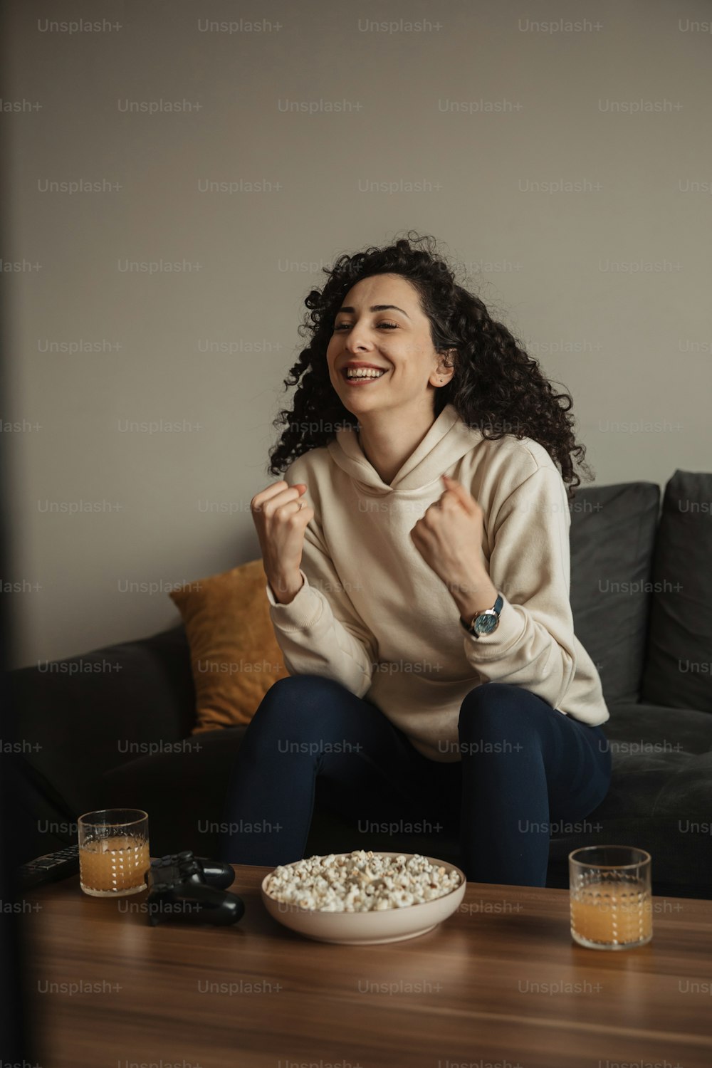 a woman sitting on a couch in front of a plate of popcorn