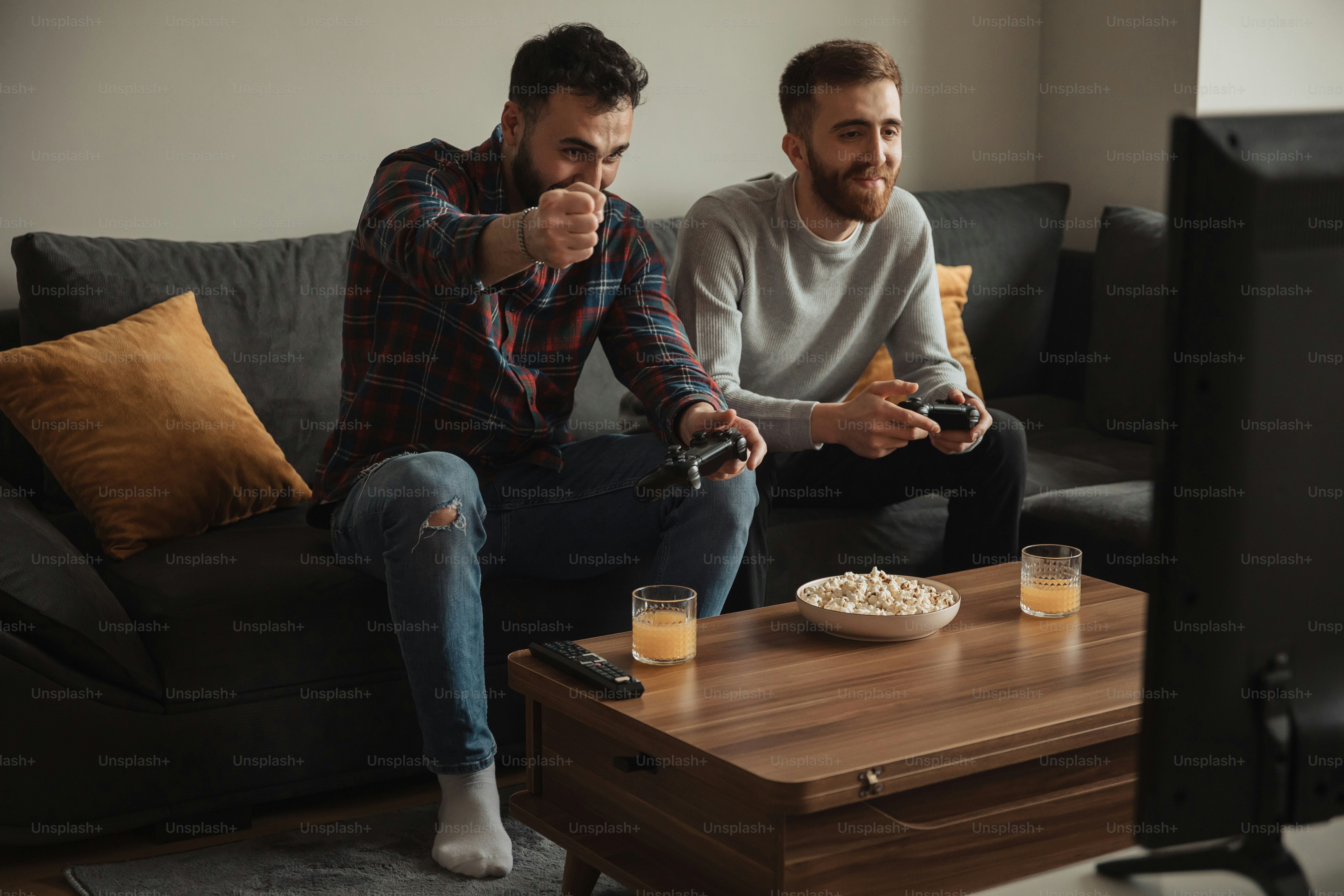 two men sitting on a couch playing a video game