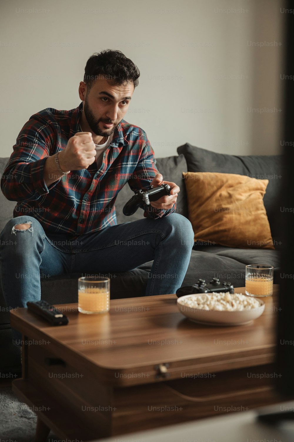 a man sitting on a couch holding a remote control