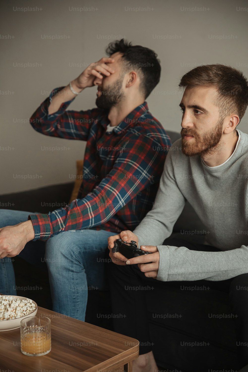ソファに座ってビデオゲームをしている2人の男性