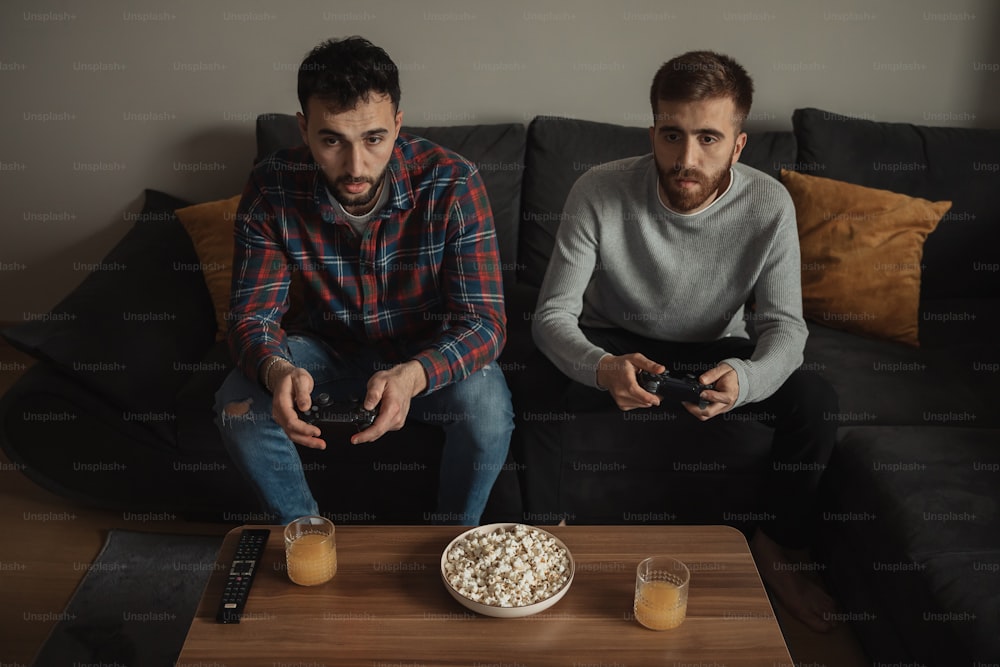 two men sitting on a couch playing video games