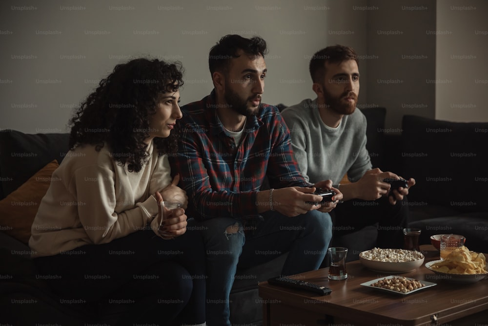 three people sitting on a couch playing a video game