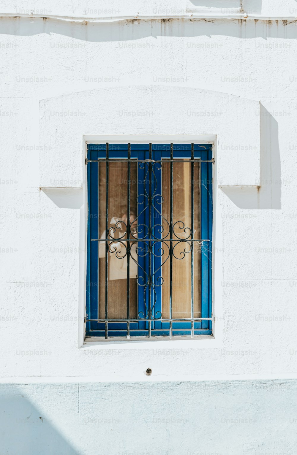 a white building with a blue window and bars