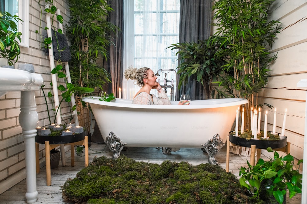 a bride and groom kissing in a bathtub surrounded by greenery