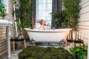 a bride and groom kissing in a bathtub surrounded by greenery