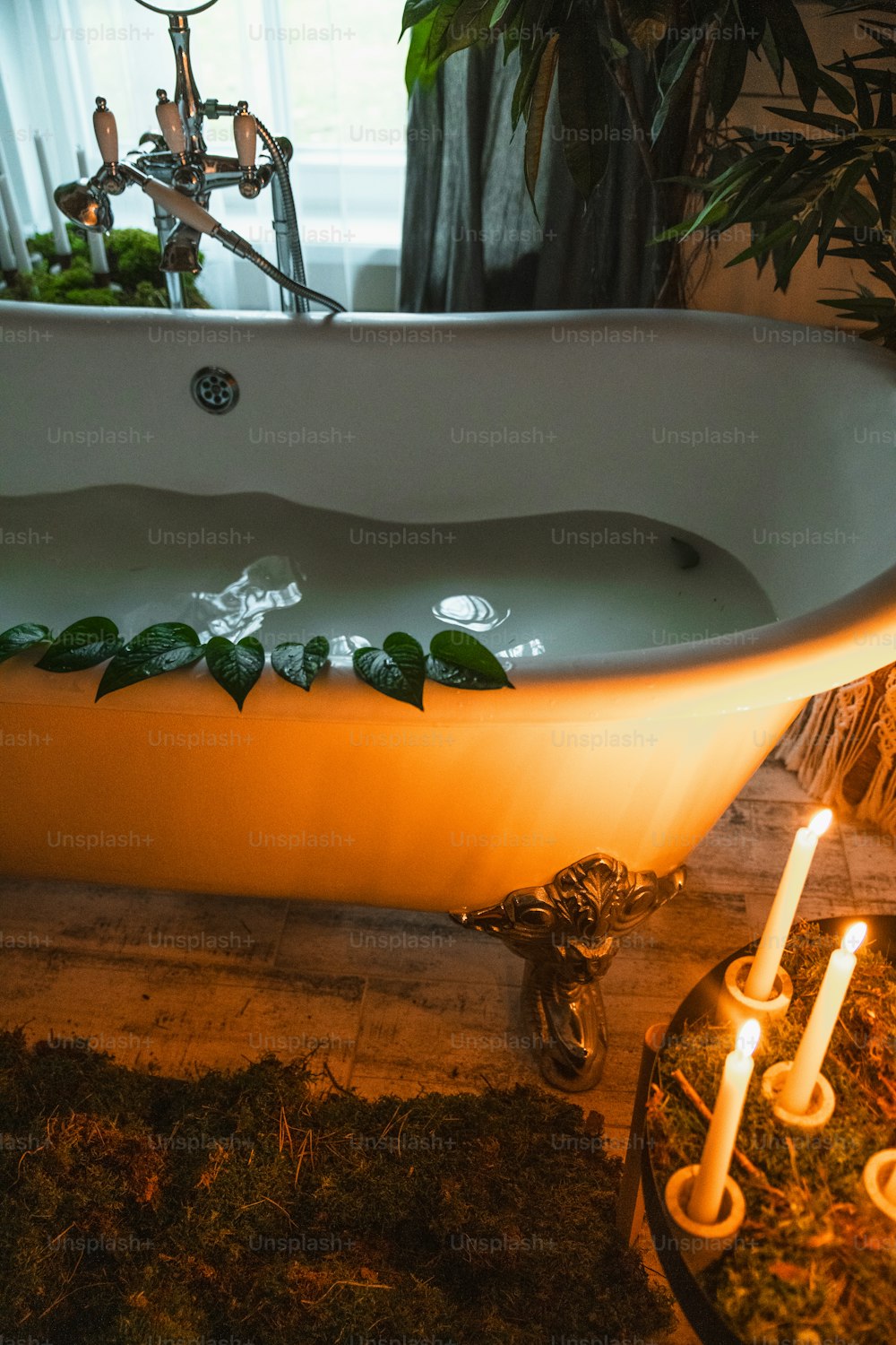 a bathtub with candles on the floor next to it