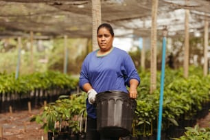 a woman holding a bucket in a greenhouse