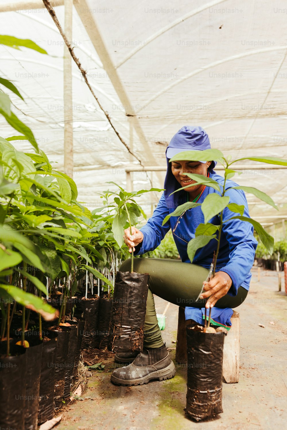a woman in a blue jacket and goggles working in a greenhouse