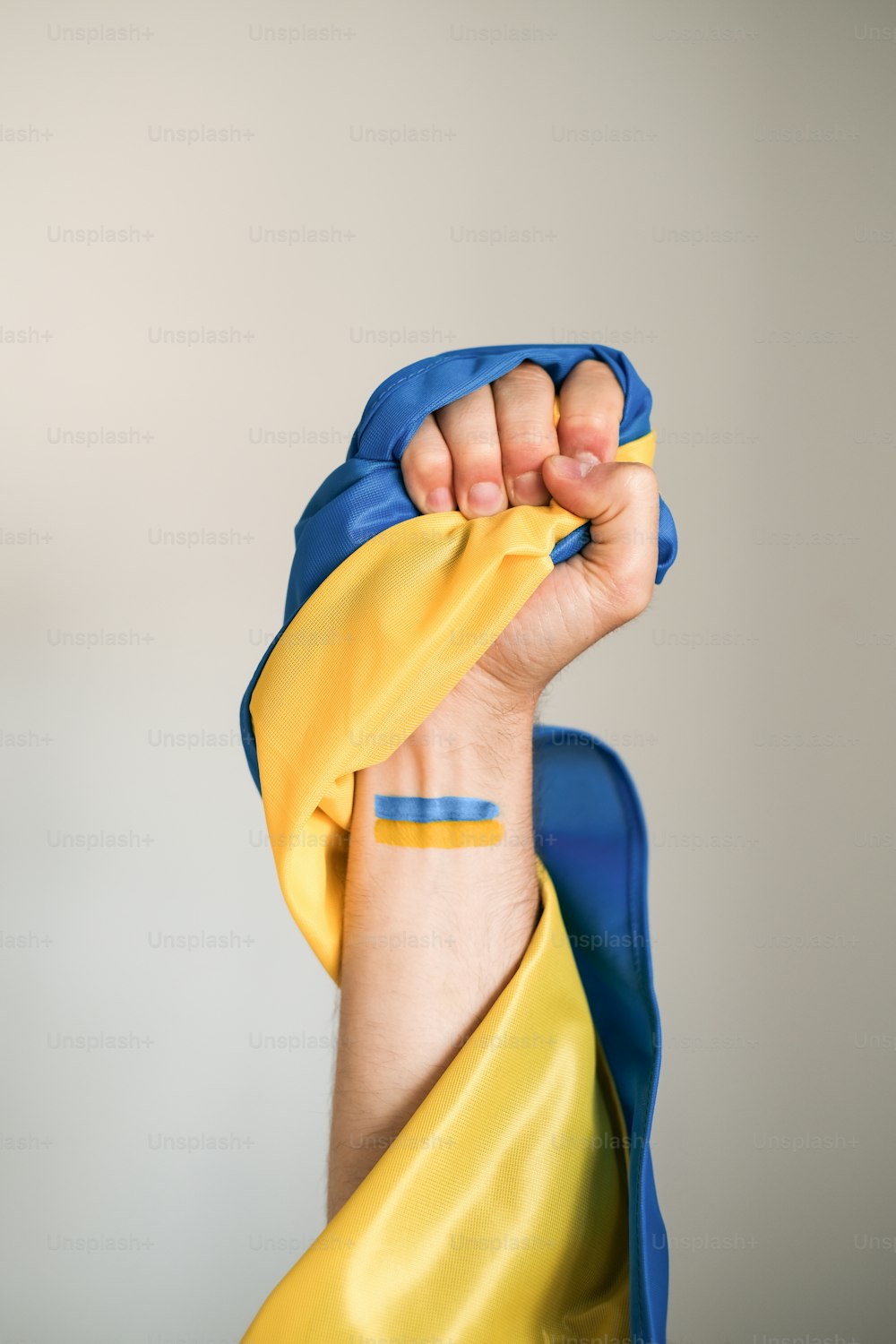 una persona con una sciarpa gialla e blu che copre il viso