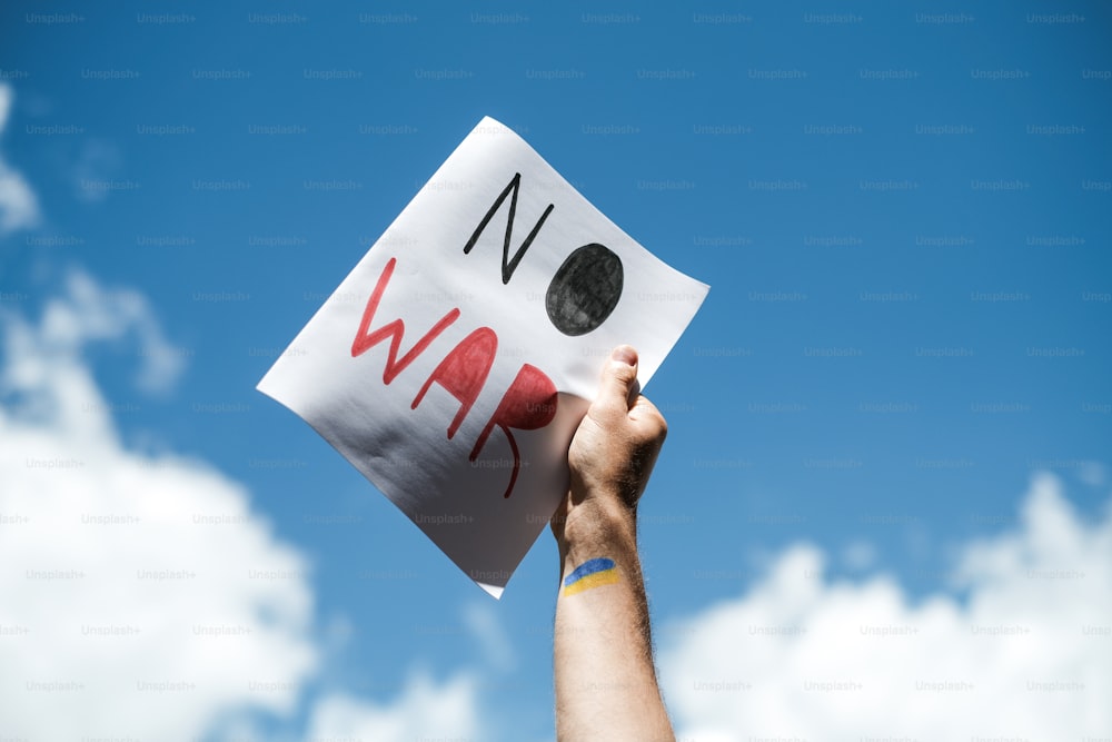 Una persona sosteniendo un cartel que dice no a la guerra