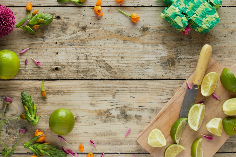 a cutting board with limes and flowers on it