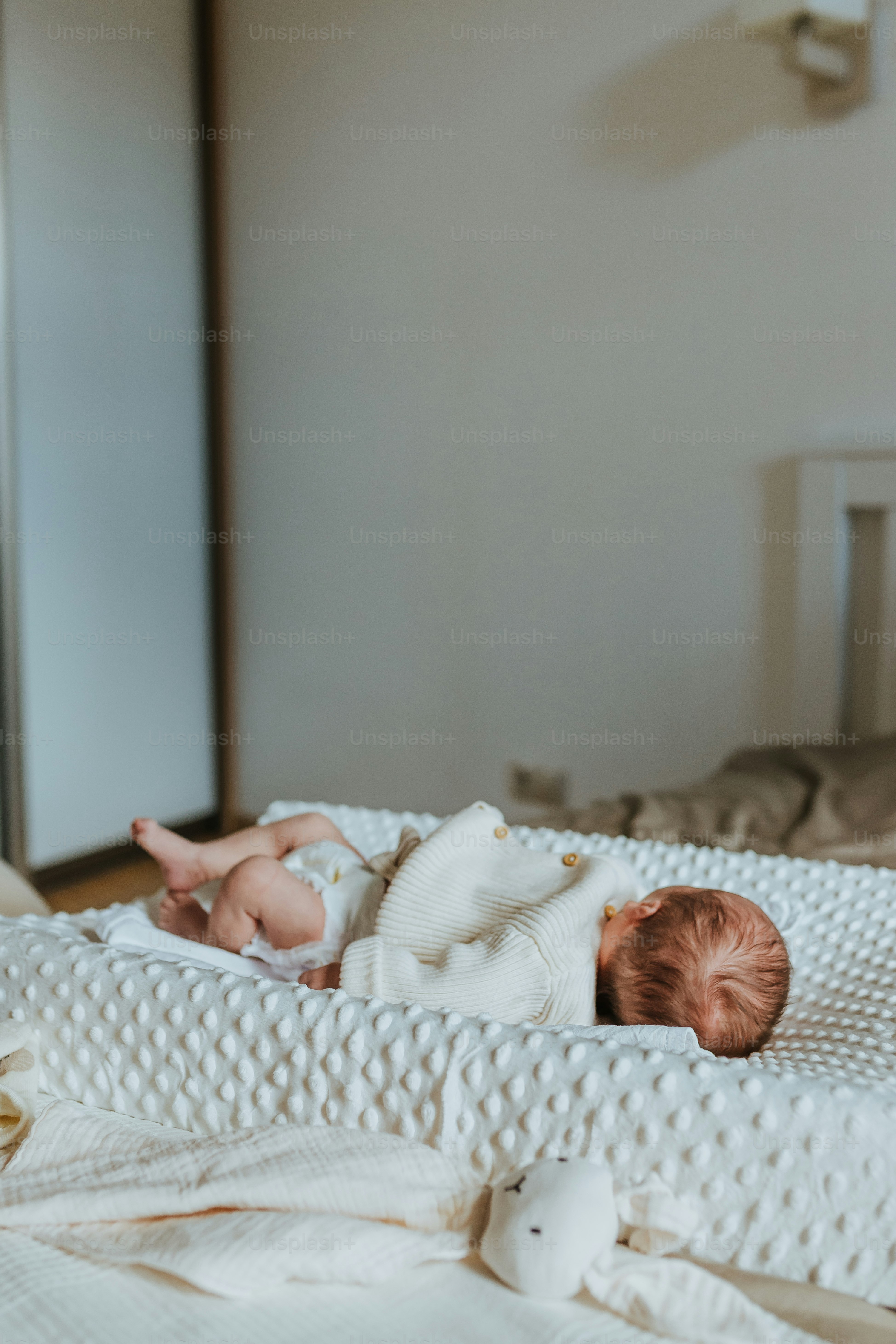 um bebê deitado em cima de uma cama branca