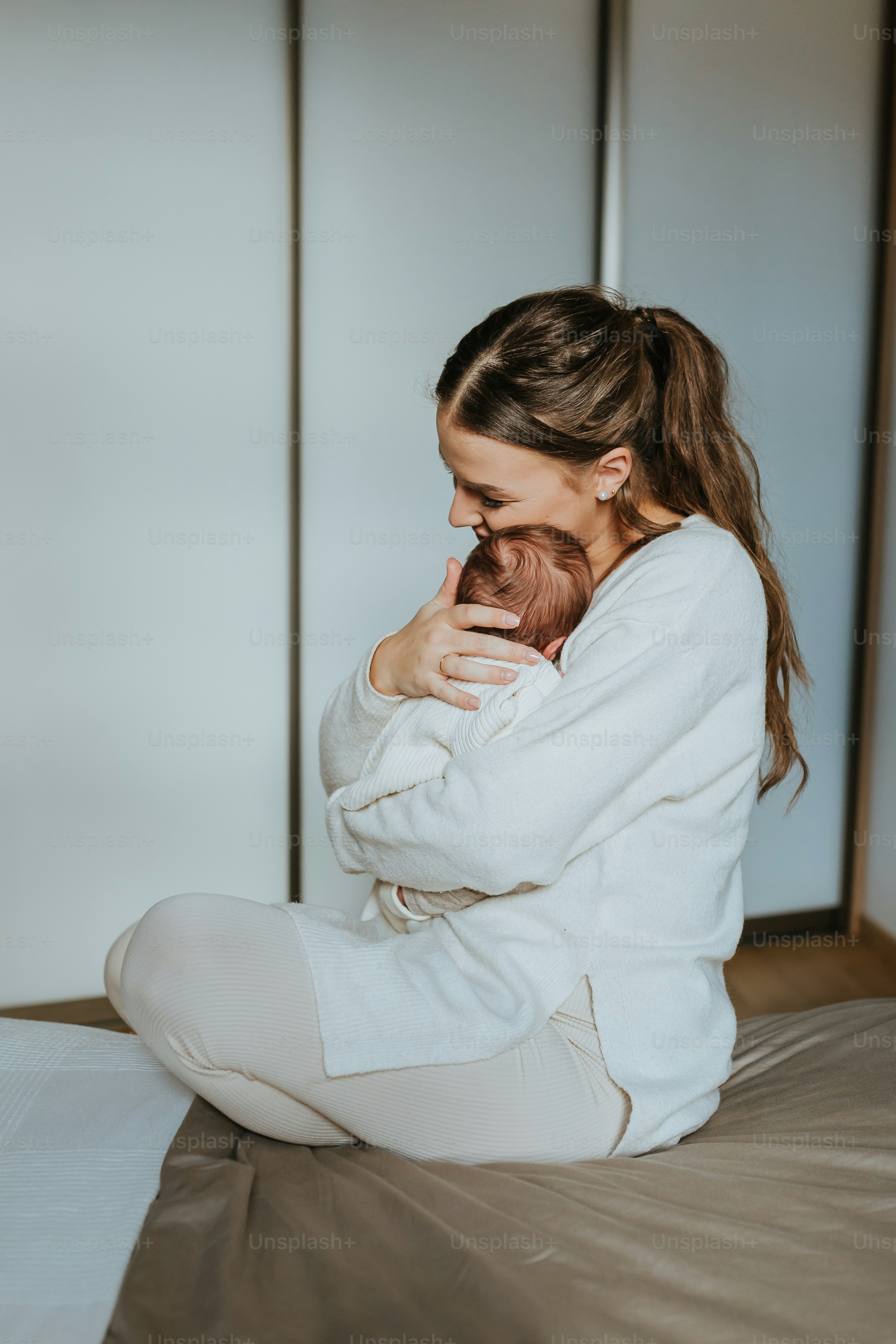 a woman sitting on a bed holding a baby
