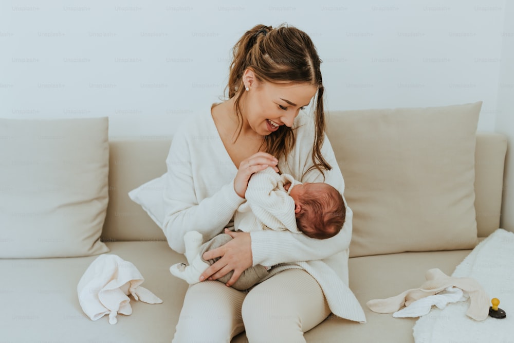 a woman sitting on a couch holding a baby