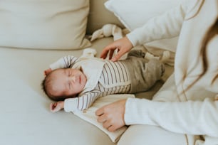 a woman is holding a baby on a couch