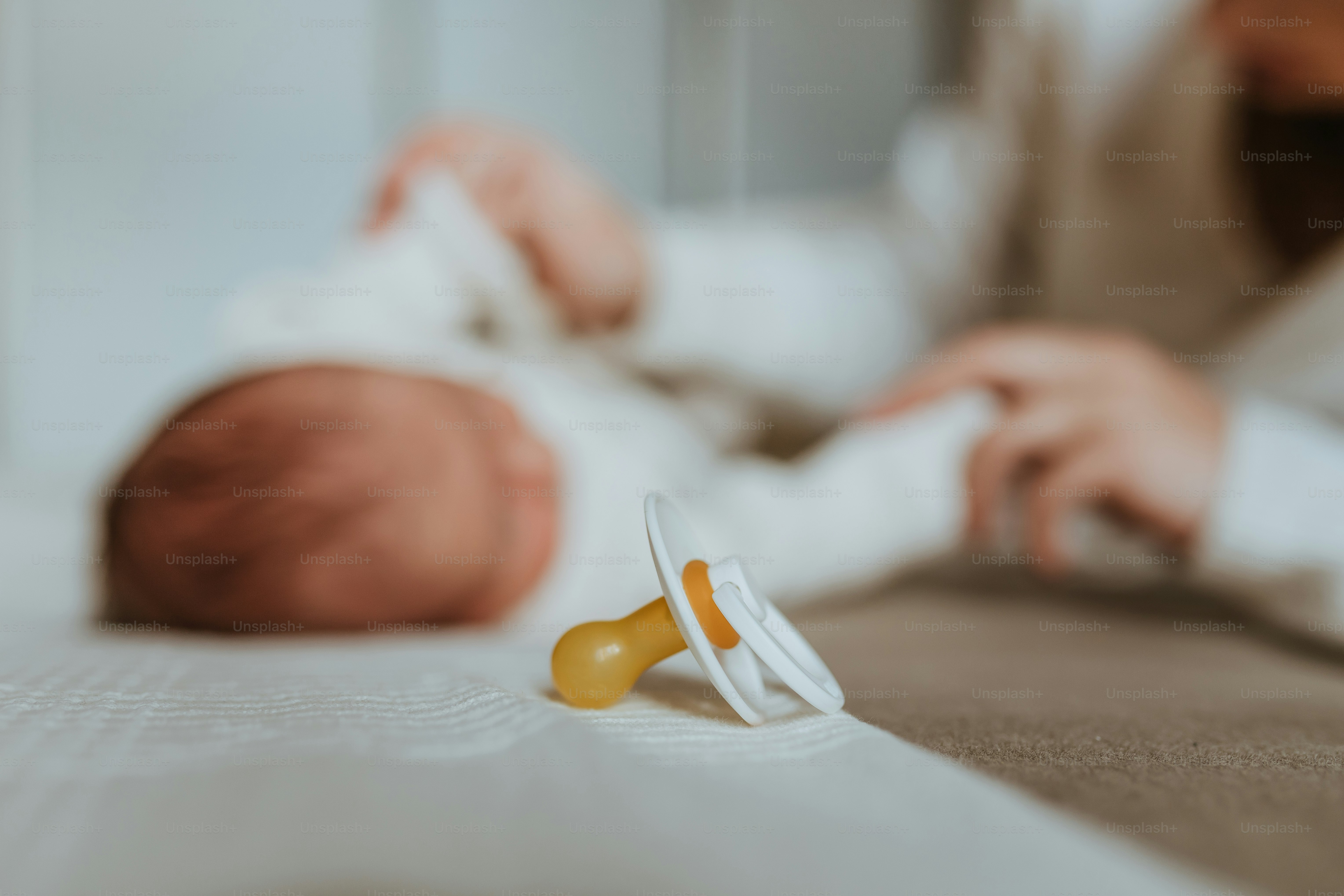 Ein Baby, das mit einem Schnuller im Mund auf einem Bett liegt