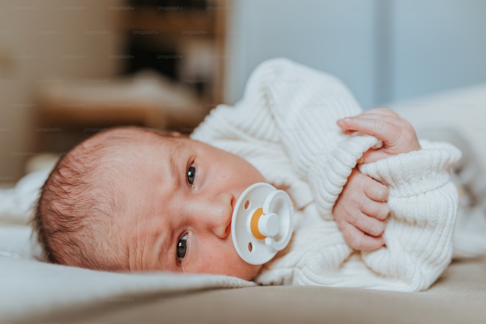 a baby with a pacifier laying on a bed