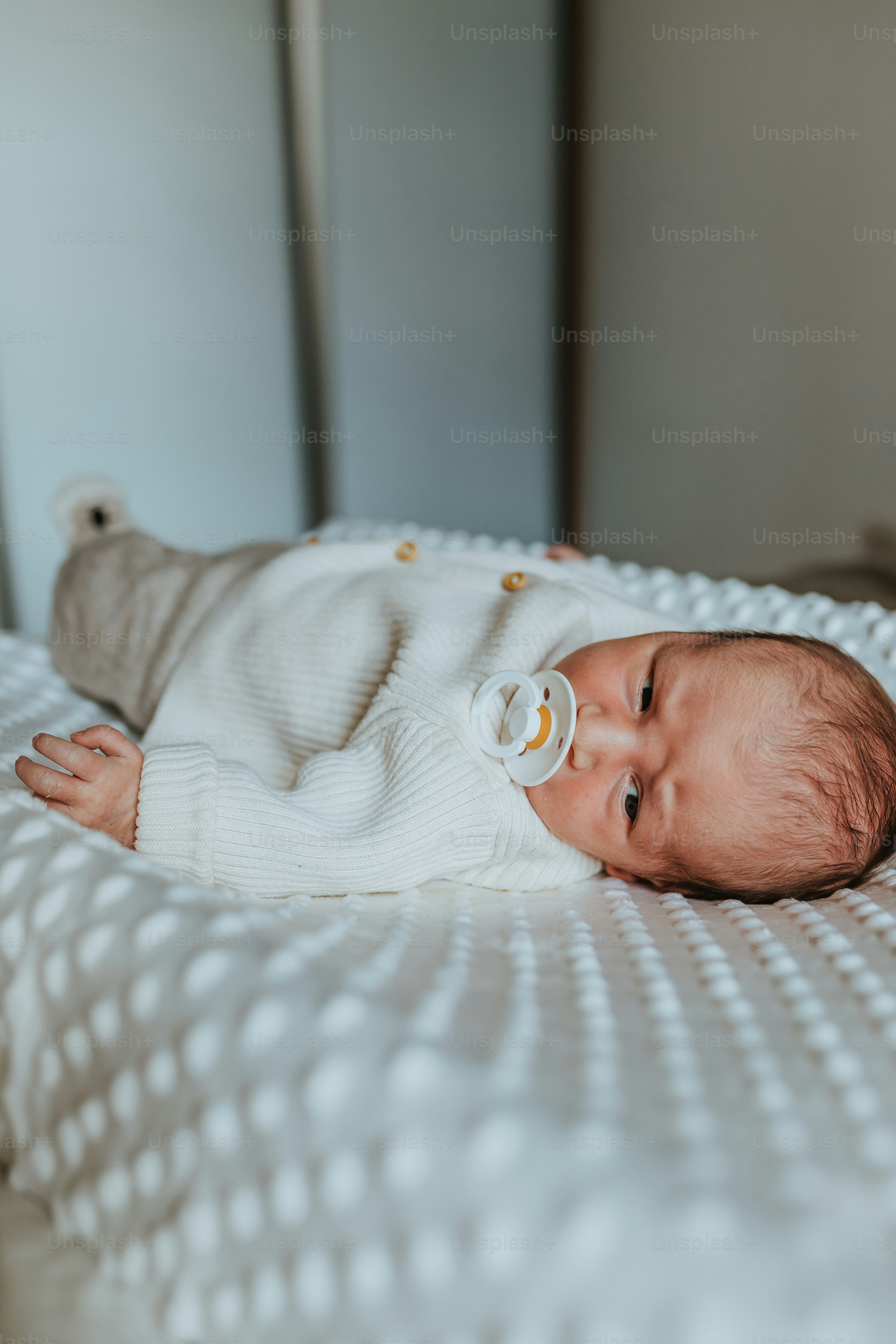 a baby laying on a bed with a pacifier in its mouth