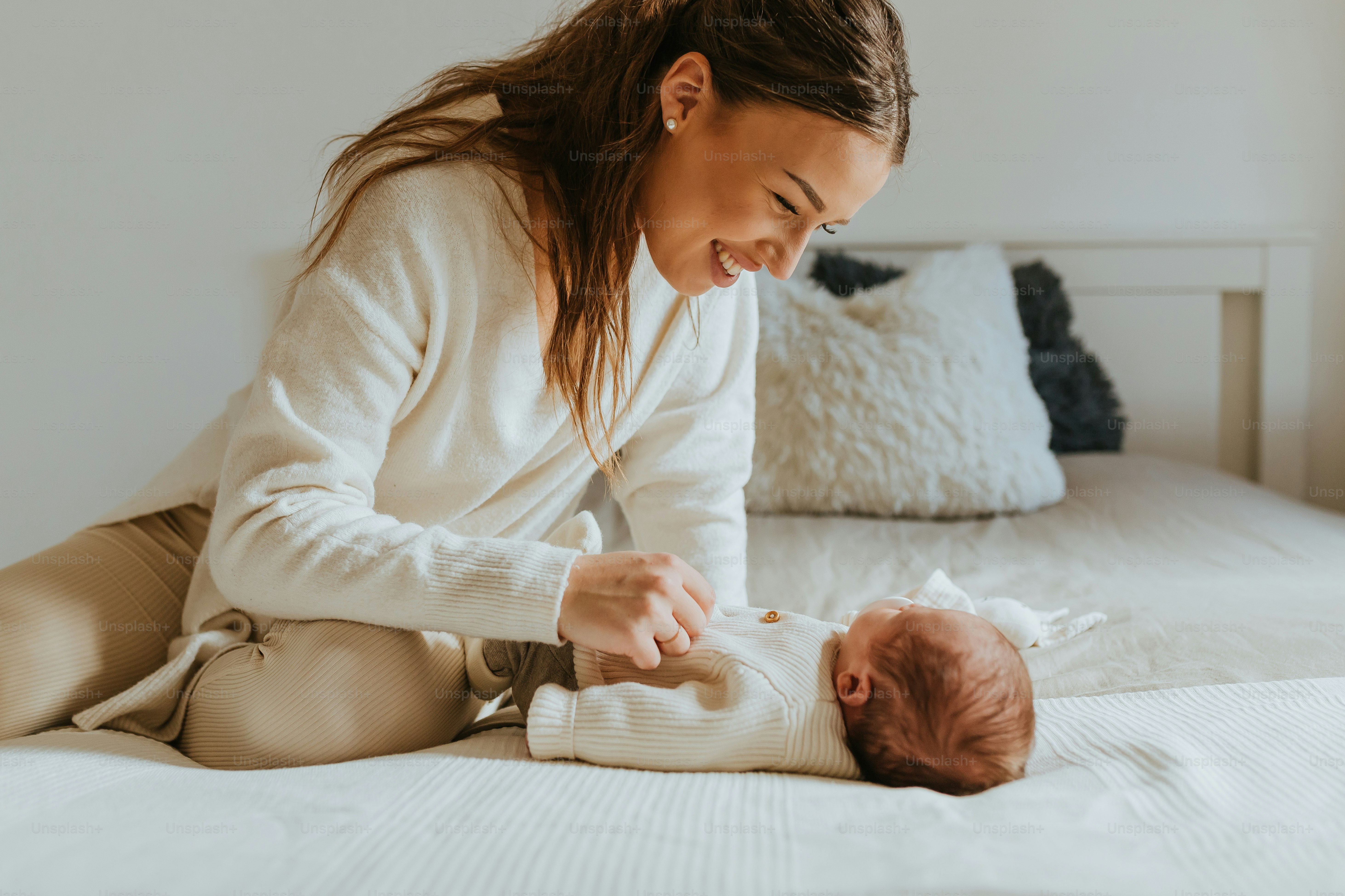 uma mulher está brincando com um bebê em uma cama