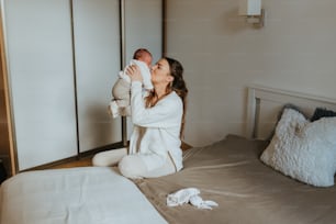 a woman sitting on a bed holding a baby