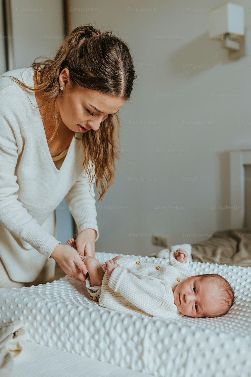 赤ちゃんのおむつにボタンをかける女性