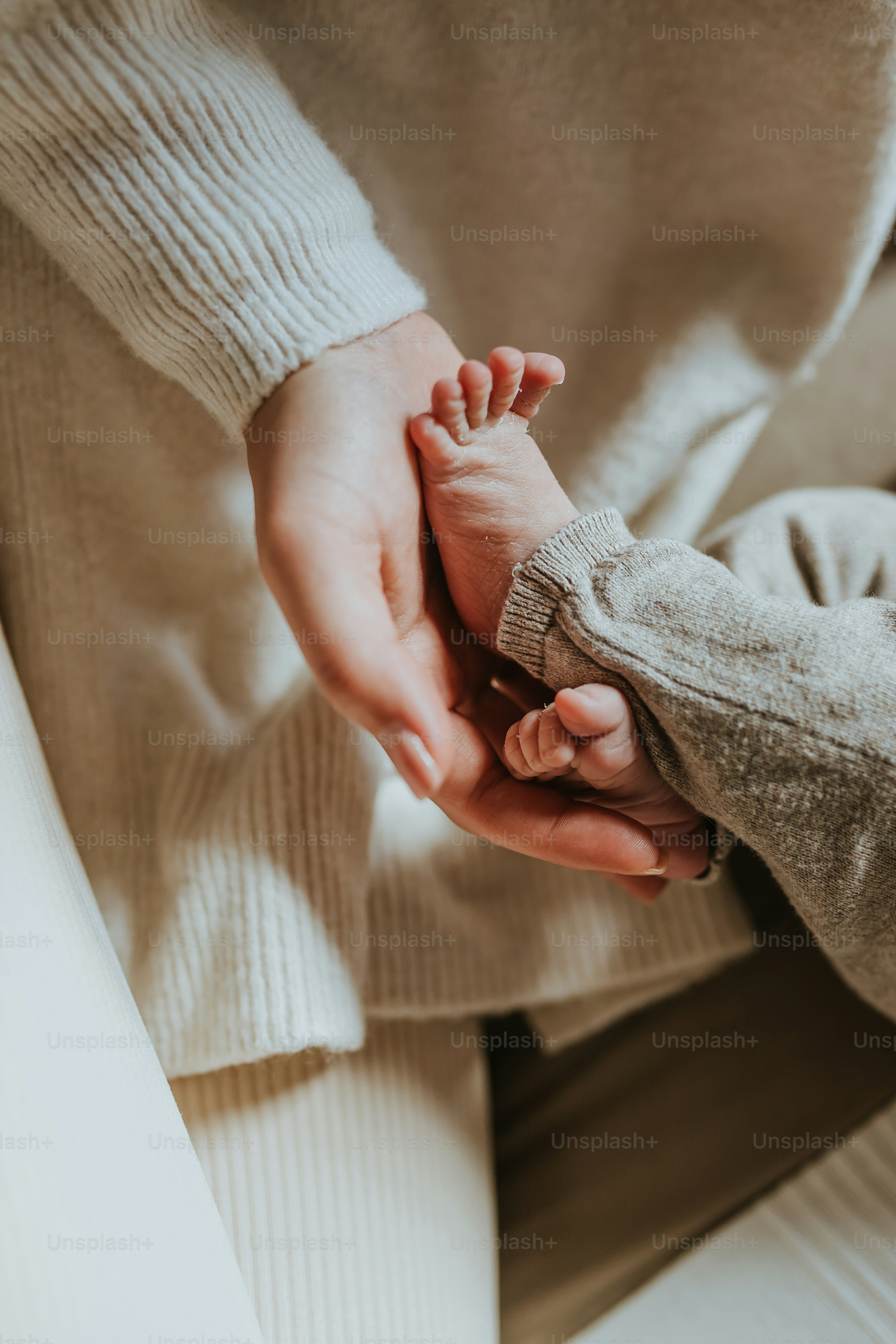 Une femme tenant la main d’un bébé assise sur un canapé