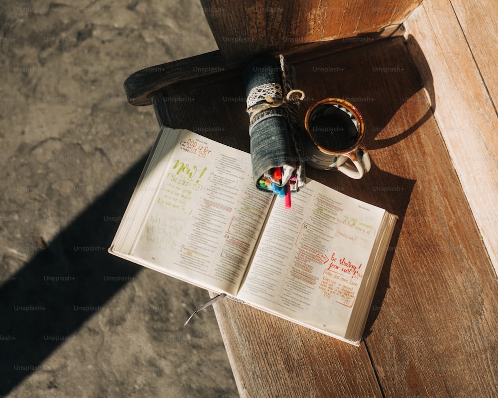 ein offenes Buch und eine Tasse Kaffee auf einem Holztisch