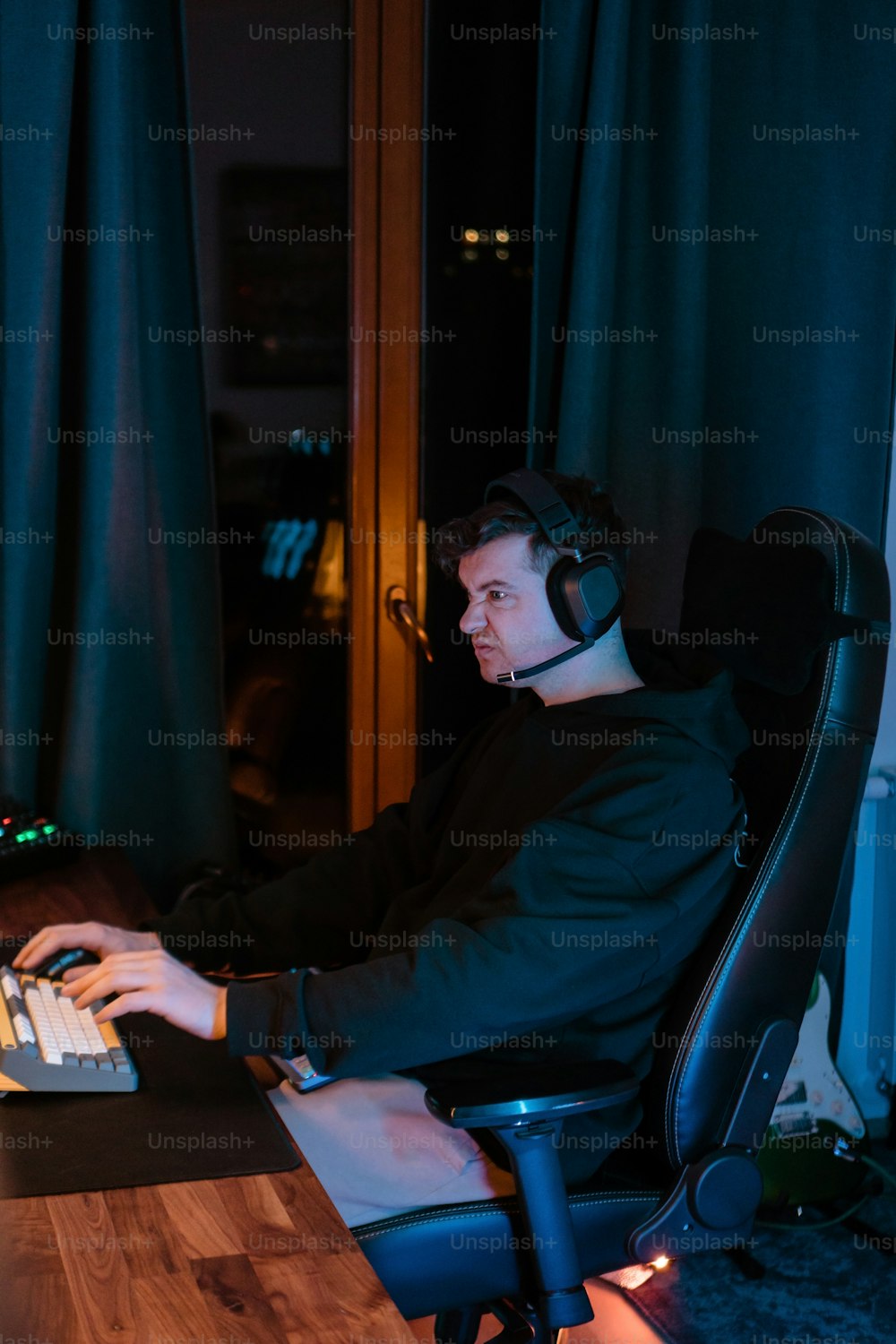 ノートパソコンとヘッドフォンをつけて机に座っている男性