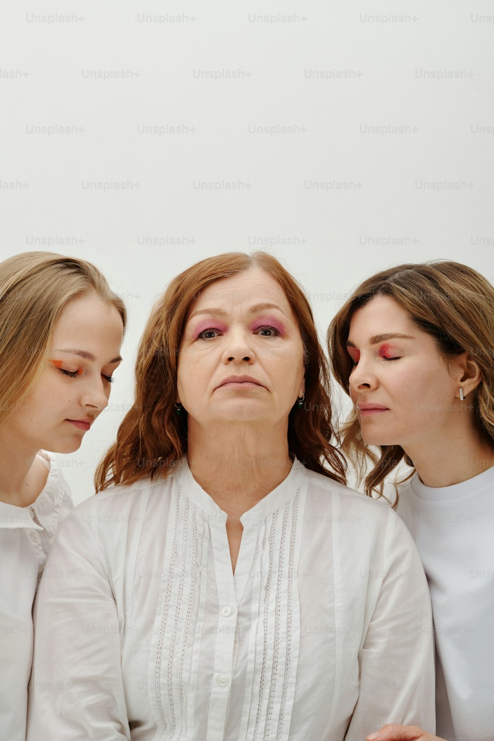 three women standing next to each other with their eyes closed