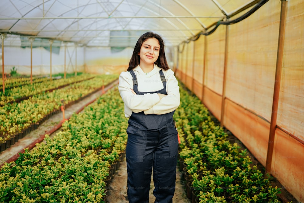 a woman standing in a greenhouse with her arms crossed