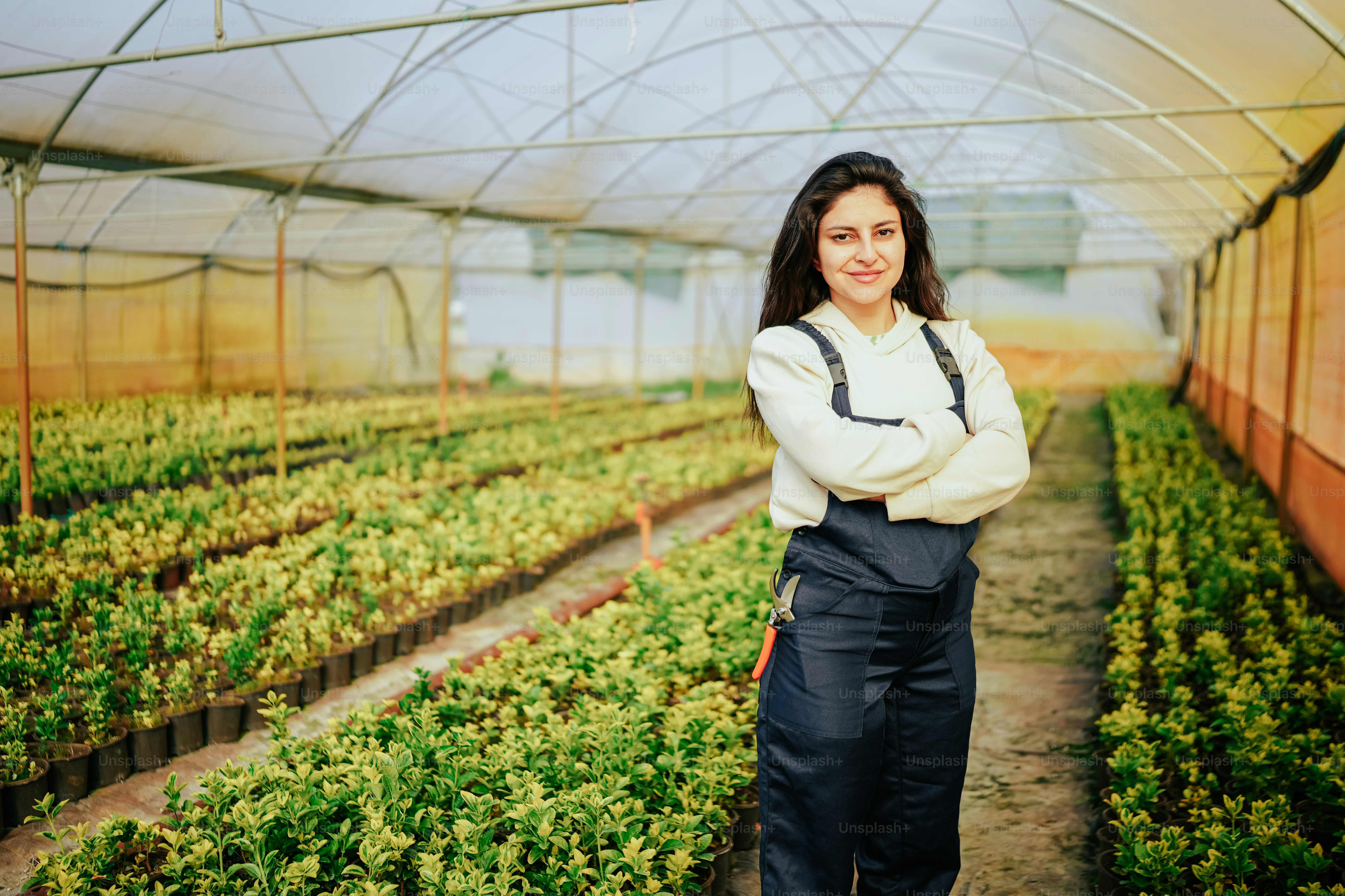 a woman standing in a greenhouse with her arms crossed